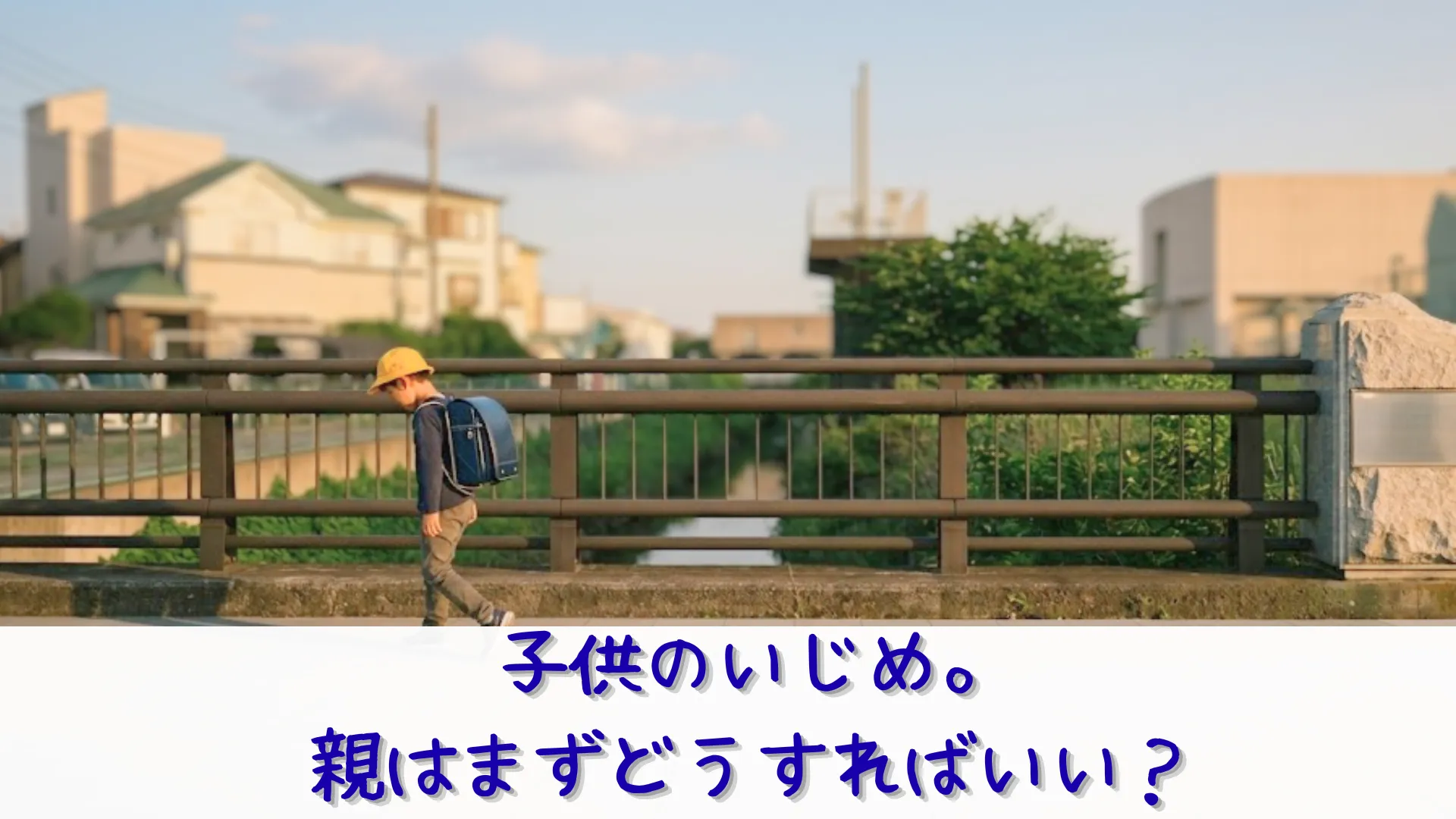 黄色い帽子を被りランドセルを背負った小学生の男の子が、一人寂しそうに橋を歩いて下校している様子。